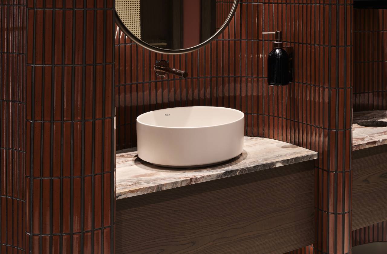 Los espacios de baño son las zonas más íntimas del restaurante y en ellos se ha optado por un diseño de líneas curvas que invita al confort. El lavabo sobre encimera de Fineceramic® Inspira Round ofrece un contrapunto orgánico a las singulares paredes curvas de los baños. La grifería electrónica de lavabo L30-E añade un plus de diseño al espacio y garantiza la eficiencia hídrica, en línea con el concepto del «Árbol de la vida». Entre los accesorios se encuentran la percha Cubica y el escobillero de pared mural Victoria, modelos minimalistas y discretos que ofrecen la máxima funcionalidad. Por otro lado, el inodoro suspendido Rimless Dama, con asiento con caída amortiguada y placa de accionamiento dual In-Wall PL10 (One), aporta un toque de modernidad y complementa el estilo acogedor y natural del espacio de baño.4