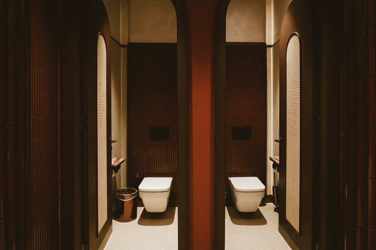 Los espacios de baño son las zonas más íntimas del restaurante y en ellos se ha optado por un diseño de líneas curvas que invita al confort. El lavabo sobre encimera de Fineceramic® Inspira Round ofrece un contrapunto orgánico a las singulares paredes curvas de los baños. La grifería electrónica de lavabo L30-E añade un plus de diseño al espacio y garantiza la eficiencia hídrica, en línea con el concepto del «Árbol de la vida». Entre los accesorios se encuentran la percha Cubica y el escobillero de pared mural Victoria, modelos minimalistas y discretos que ofrecen la máxima funcionalidad. Por otro lado, el inodoro suspendido Rimless Dama, con asiento con caída amortiguada y placa de accionamiento dual In-Wall PL10 (One), aporta un toque de modernidad y complementa el estilo acogedor y natural del espacio de baño.10