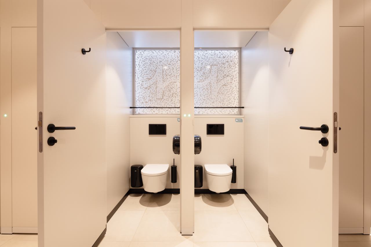 Los diseños modulares personalizables se adaptan a los diversos perfiles de usuarios. Mediante el uso de formas orgánicas y elementos inspirados en la naturaleza, estos aseos públicos ofrecen a los visitantes un entorno relajante y reparador. Su diseño combina la calidez de los materiales naturales como la piedra, la madera y las fibras texturizadas con la pulcritud y la durabilidad que requieren los espacios públicos. Los lavabos circulares e inodoros suspendidos de la colección Inspira de Roca encajan a la perfección en este ambiente, garantizando tanto la funcionalidad como la estética adecuadas. Los aseos masculinos cuentan con urinarios Chic y sistemas de descarga electrónicos Sentronic para una mayor higiene y comodidad, mientras que los aseos para personas con movilidad reducida priman la accesibilidad y el confort. Estos cuentan con asas de baño Access en un relajante acabado blanco, placas de descarga electrónica en cristal negro y espejos basculantes diseñados para adaptarse a las diferentes alturas y necesidades de los usuarios. Estos productos Roca, cuidadosamente seleccionados, permiten a cada visitante disfrutar de un momento de confort y bienestar en un espacio funcional y bien diseñado.4