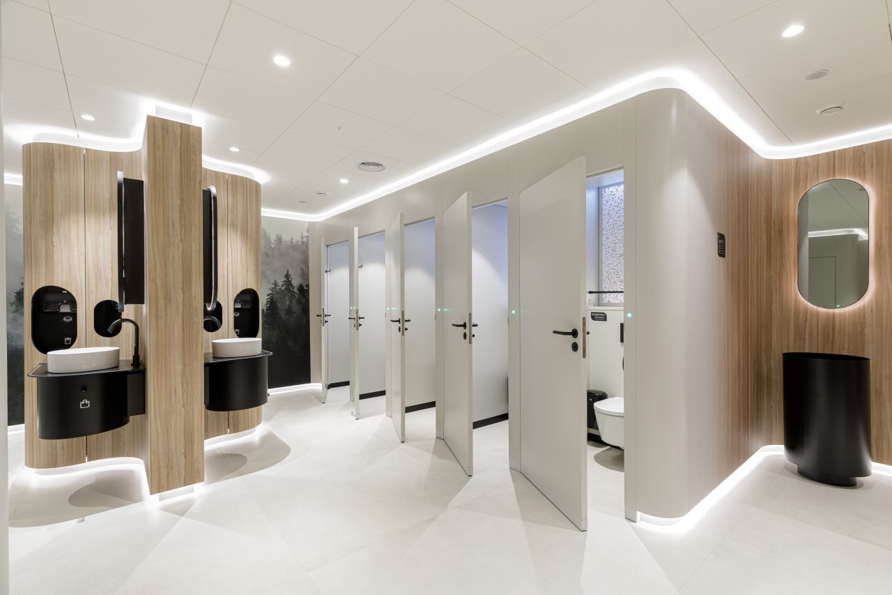 Los diseños modulares personalizables se adaptan a los diversos perfiles de usuarios. Mediante el uso de formas orgánicas y elementos inspirados en la naturaleza, estos aseos públicos ofrecen a los visitantes un entorno relajante y reparador. Su diseño combina la calidez de los materiales naturales como la piedra, la madera y las fibras texturizadas con la pulcritud y la durabilidad que requieren los espacios públicos. Los lavabos circulares e inodoros suspendidos de la colección Inspira de Roca encajan a la perfección en este ambiente, garantizando tanto la funcionalidad como la estética adecuadas. Los aseos masculinos cuentan con urinarios Chic y sistemas de descarga electrónicos Sentronic para una mayor higiene y comodidad, mientras que los aseos para personas con movilidad reducida priman la accesibilidad y el confort. Estos cuentan con asas de baño Access en un relajante acabado blanco, placas de descarga electrónica en cristal negro y espejos basculantes diseñados para adaptarse a las diferentes alturas y necesidades de los usuarios. Estos productos Roca, cuidadosamente seleccionados, permiten a cada visitante disfrutar de un momento de confort y bienestar en un espacio funcional y bien diseñado.2