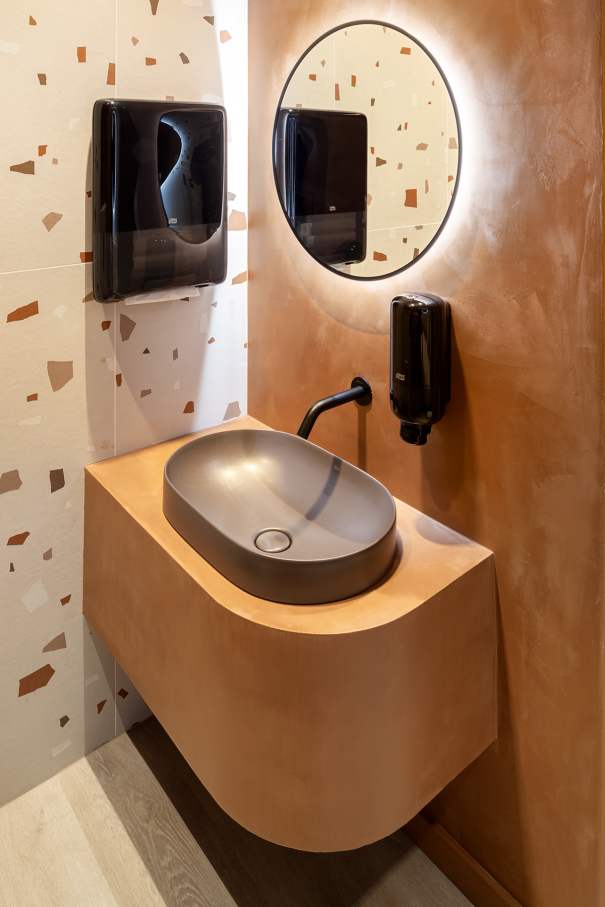 La prioridad en el diseño interior del hotel es garantizar que los huéspedes se vayan con una sonrisa, sintiéndose relajados y completamente satisfechos. Adoptando el enfoque minimalista del hygge, el diseño transmite una agradable sensación de confort a través de una cuidada selección de colores y mobiliario en materiales naturales con suaves curvas y formas orgánicas. En perfecta sintonía con la filosofía hygge, las líneas suaves y las formas redondeadas del lavabo Beyond de color café y del inodoro y bidé Inspira irradian relajación, calidez y armonía. El diseño de la colección Ona, inspirado en la naturaleza, se suma a la estética relajante. Los bidés y lavabos suspendidos contribuyen a crear una sensación de amplitud y equilibrio que evoca la serenidad de los paisajes tranquilos. De esta forma, el confort y el hygge se transmiten a todos los huéspedes del hotel. Los aseos públicos para hombres cuentan con los minimalistas urinarios Proton y los aseos accesibles están equipados con inodoros Access y asas de baño, garantizando un entorno acogedor e inclusivo para todos.24