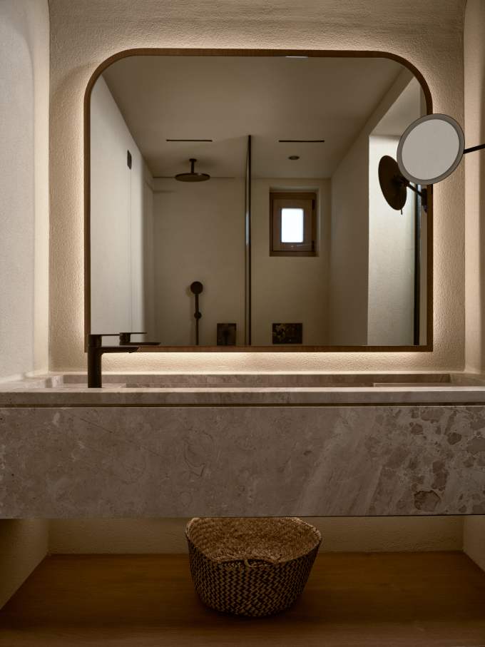 El interior de este complejo hotelero presenta una estética minimalista en tonos tierra, materiales de primera calidad y una iluminación tenue para crear una atmósfera relajante, propia de un spa. Los baños cuentan con una amplia encimera suspendida de mármol y un sobrio lavabo integrado, complementado con la elegante grifería Cala en negro mate, que crea un llamativo contraste con los tonos más claros del mármol y las paredes.1