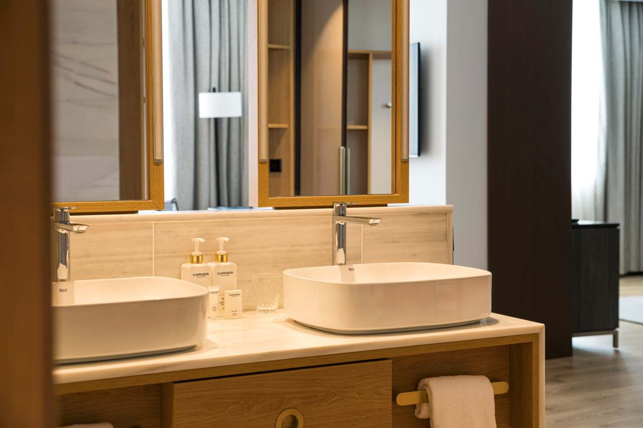 Los baños del Gran Meliá Torre Melina ofrecen una experiencia sofisticada y confortable, realzada por los productos de alta gama de Roca. En las habitaciones Supreme, los huéspedes pueden disfrutar de un exclusivo baño con la original bañera de Stonex® Kauai y la grifería de baño-ducha. Otras habitaciones cuentan con innovadoras soluciones para el espacio de ducha, como los platos de ducha de Stonex® Terran y la grifería termostática T-500, que proporcionan una sensación única en la ducha. Los aseos públicos del hotel cuentan con modernos y funcionales lavabos sobre encimera de la colección Ona, urinarios Mural e inodoros adosados a pared The Gap Round. Los resistentes materiales de Roca Stonex® y Fineceramic® no sólo contribuyen a optimizar los estándares de higiene, sino que también aumentan la eficiencia operativa en todo el hotel, reflejando el compromiso de este establecimiento con la excelencia hotelera.8