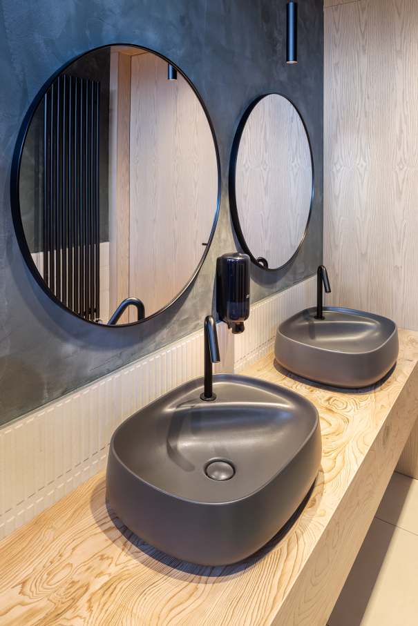 La prioridad en el diseño interior del hotel es garantizar que los huéspedes se vayan con una sonrisa, sintiéndose relajados y completamente satisfechos. Adoptando el enfoque minimalista del hygge, el diseño transmite una agradable sensación de confort a través de una cuidada selección de colores y mobiliario en materiales naturales con suaves curvas y formas orgánicas. En perfecta sintonía con la filosofía hygge, las líneas suaves y las formas redondeadas del lavabo Beyond de color café y del inodoro y bidé Inspira irradian relajación, calidez y armonía. El diseño de la colección Ona, inspirado en la naturaleza, se suma a la estética relajante. Los bidés y lavabos suspendidos contribuyen a crear una sensación de amplitud y equilibrio que evoca la serenidad de los paisajes tranquilos. De esta forma, el confort y el hygge se transmiten a todos los huéspedes del hotel. Los aseos públicos para hombres cuentan con los minimalistas urinarios Proton y los aseos accesibles están equipados con inodoros Access y asas de baño, garantizando un entorno acogedor e inclusivo para todos.45