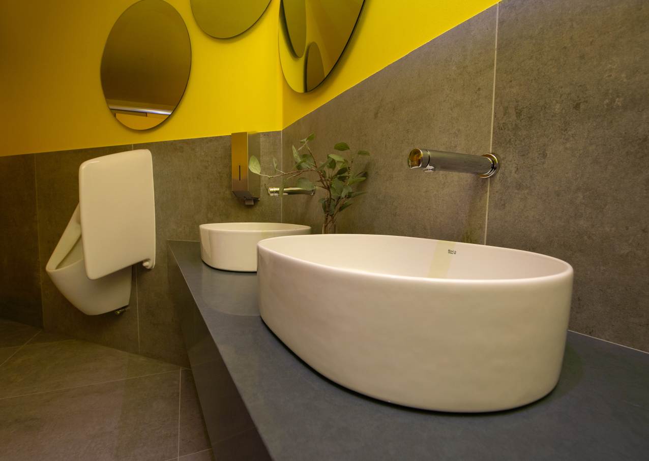 En línea con esta premisa, este espacio, caracterizado por su llamativo y colorido diseño, innovación y sostenibilidad, incorporó las soluciones de baño de Roca más avanzadas, mostrándolas al público. Una serie de vistosos conos aportaron sombra y ventilaron de forma natural el espacio; en su interior los inodoros Inspira y Beyond de Roca fueron el complemento perfecto a las formas fluidas del pabellón y los objetivos de sostenibilidad gracias a su tecnología de ahorro de agua. Por otro lado, los lavabos Inspira, los espejos Iridia y los separadores de urinario Wing replicaban la estética lúdica y sofisticada del entorno. Propuestas como la placa de accionamiento electrónica EP1 y la grifería temporizada Avant demostraron el compromiso de Roca con la eficiencia hídrica, reflejando a la perfección los principios de economía circular y la filosofía del diseño centrado en las personas.5