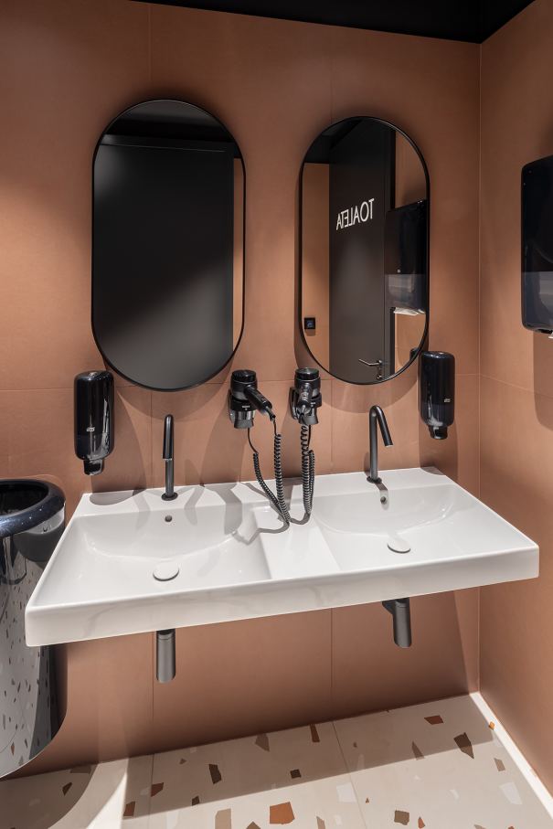 La prioridad en el diseño interior del hotel es garantizar que los huéspedes se vayan con una sonrisa, sintiéndose relajados y completamente satisfechos. Adoptando el enfoque minimalista del hygge, el diseño transmite una agradable sensación de confort a través de una cuidada selección de colores y mobiliario en materiales naturales con suaves curvas y formas orgánicas. En perfecta sintonía con la filosofía hygge, las líneas suaves y las formas redondeadas del lavabo Beyond de color café y del inodoro y bidé Inspira irradian relajación, calidez y armonía. El diseño de la colección Ona, inspirado en la naturaleza, se suma a la estética relajante. Los bidés y lavabos suspendidos contribuyen a crear una sensación de amplitud y equilibrio que evoca la serenidad de los paisajes tranquilos. De esta forma, el confort y el hygge se transmiten a todos los huéspedes del hotel. Los aseos públicos para hombres cuentan con los minimalistas urinarios Proton y los aseos accesibles están equipados con inodoros Access y asas de baño, garantizando un entorno acogedor e inclusivo para todos.43