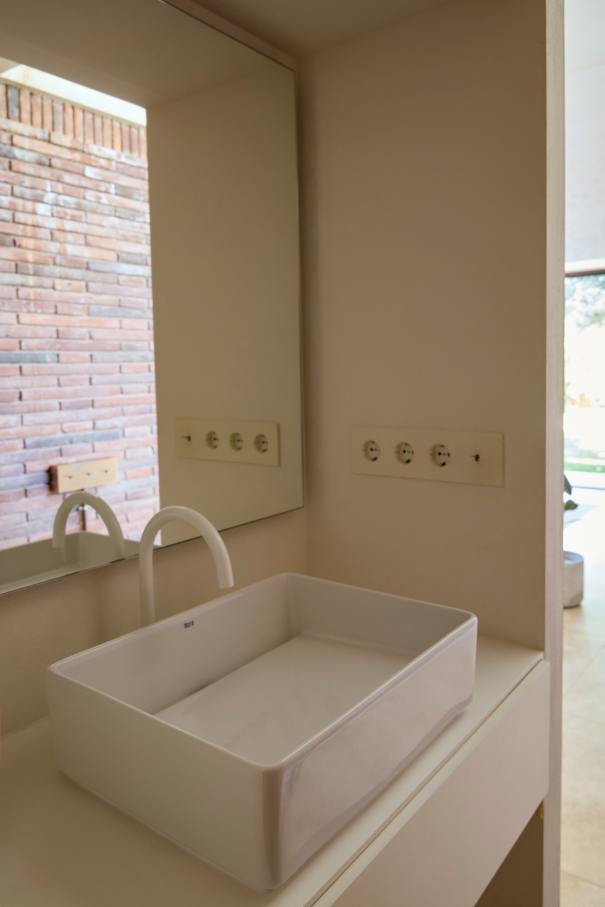 La distribución de Casa IV transforma el baño en un elemento fluido del espacio vital, contribuyendo a mejorar la experiencia de los habitantes de la vivienda. La incorporación de la bañera, el inodoro y el lavabo sobre encimera de la colección Tura genera una sensación de calma y sofisticación, mientras que la grifería Stripes de la colección Nu introduce un toque de dinamismo. La bañera trasciende lo funcional, convirtiéndose en el centro de atención del dormitorio y en un símbolo del estilo de vida mediterráneo. Esta vivienda es un ejemplo de cómo los productos Roca mejoran la experiencia de los usuarios, creando una mezcla perfecta de funcionalidad y diseño, en línea con la filosofía del proyecto, basada en la elegancia discreta y en los detalles cuidadosamente escogidos.26