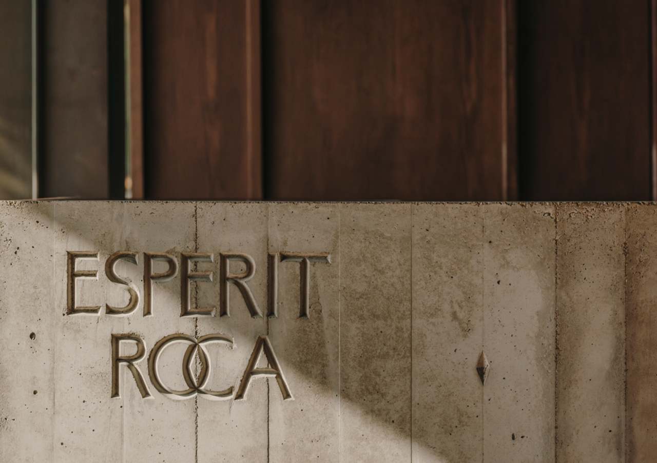 El diseño de Carulla para el restaurante, también denominado Esperit Roca, combina suaves tonos tierra con paredes de hormigón, detalles en piedra y una cálida iluminación para crear un espacio acogedor que transmite una sutil sofisticación. En los espacios de baño se ha optado por el inodoro suspendido Roca Rimless® de la colección Tura, concebida por el diseñador, para lograr una estética unificada. Al igual que el propio restaurante, el diseño escultural del inodoro está inspirado en el paisaje mediterráneo de la región. Otros elementos seleccionados incluyen la grifería electrónica Loft, que se integra a la perfección en los lavabos de piedra. La silueta casi industrial de la grifería complementa la solidez de la piedra y el espacio en penumbra, mientras que la tecnología electrónica aporta eficiencia hídrica y facilidad de uso.