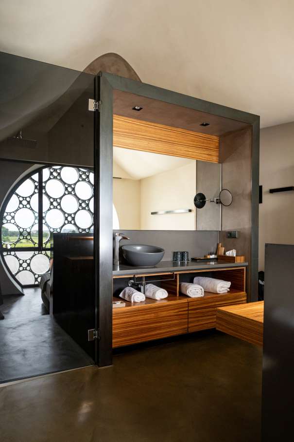 El diseño de este hotel boutique de 13 habitaciones se inspira en el apilado horizontal de las botellas de cava y en la técnica del trencadís de Antoni Gaudí. Las líneas sinuosas, los grandes ventanales circulares y los motivos geométricos, junto con el uso de materiales naturales, crean un conjunto equilibrado en perfecta armonía con el entorno. Los modernos baños de planta abierta cuentan con lavabos Bol en acabado grafito, la elegante grifería de lavabo Thesis y los originales inodoros Happening. La decidida apuesta por la sostenibilidad, patente en el cuidado diseño del edificio y las buenas prácticas sostenibles, también se refleja en los productos Roca, que contribuyen a la eficiencia energética y la durabilidad.6