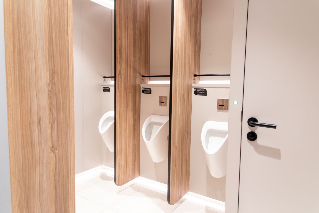 Los diseños modulares personalizables se adaptan a los diversos perfiles de usuarios. Mediante el uso de formas orgánicas y elementos inspirados en la naturaleza, estos aseos públicos ofrecen a los visitantes un entorno relajante y reparador. Su diseño combina la calidez de los materiales naturales como la piedra, la madera y las fibras texturizadas con la pulcritud y la durabilidad que requieren los espacios públicos. Los lavabos circulares e inodoros suspendidos de la colección Inspira de Roca encajan a la perfección en este ambiente, garantizando tanto la funcionalidad como la estética adecuadas. Los aseos masculinos cuentan con urinarios Chic y sistemas de descarga electrónicos Sentronic para una mayor higiene y comodidad, mientras que los aseos para personas con movilidad reducida priman la accesibilidad y el confort. Estos cuentan con asas de baño Access en un relajante acabado blanco, placas de descarga electrónica en cristal negro y espejos basculantes diseñados para adaptarse a las diferentes alturas y necesidades de los usuarios. Estos productos Roca, cuidadosamente seleccionados, permiten a cada visitante disfrutar de un momento de confort y bienestar en un espacio funcional y bien diseñado.6