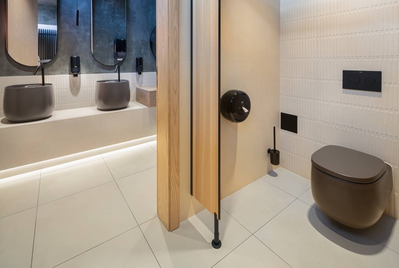 La prioridad en el diseño interior del hotel es garantizar que los huéspedes se vayan con una sonrisa, sintiéndose relajados y completamente satisfechos. Adoptando el enfoque minimalista del hygge, el diseño transmite una agradable sensación de confort a través de una cuidada selección de colores y mobiliario en materiales naturales con suaves curvas y formas orgánicas. En perfecta sintonía con la filosofía hygge, las líneas suaves y las formas redondeadas del lavabo Beyond de color café y del inodoro y bidé Inspira irradian relajación, calidez y armonía. El diseño de la colección Ona, inspirado en la naturaleza, se suma a la estética relajante. Los bidés y lavabos suspendidos contribuyen a crear una sensación de amplitud y equilibrio que evoca la serenidad de los paisajes tranquilos. De esta forma, el confort y el hygge se transmiten a todos los huéspedes del hotel. Los aseos públicos para hombres cuentan con los minimalistas urinarios Proton y los aseos accesibles están equipados con inodoros Access y asas de baño, garantizando un entorno acogedor e inclusivo para todos.11