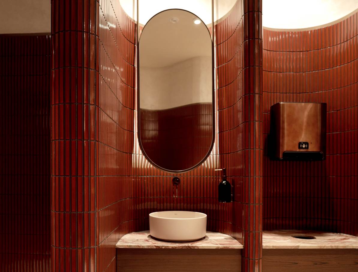 Los espacios de baño son las zonas más íntimas del restaurante y en ellos se ha optado por un diseño de líneas curvas que invita al confort. El lavabo sobre encimera de Fineceramic® Inspira Round ofrece un contrapunto orgánico a las singulares paredes curvas de los baños. La grifería electrónica de lavabo L30-E añade un plus de diseño al espacio y garantiza la eficiencia hídrica, en línea con el concepto del «Árbol de la vida». Entre los accesorios se encuentran la percha Cubica y el escobillero de pared mural Victoria, modelos minimalistas y discretos que ofrecen la máxima funcionalidad. Por otro lado, el inodoro suspendido Rimless Dama, con asiento con caída amortiguada y placa de accionamiento dual In-Wall PL10 (One), aporta un toque de modernidad y complementa el estilo acogedor y natural del espacio de baño.8