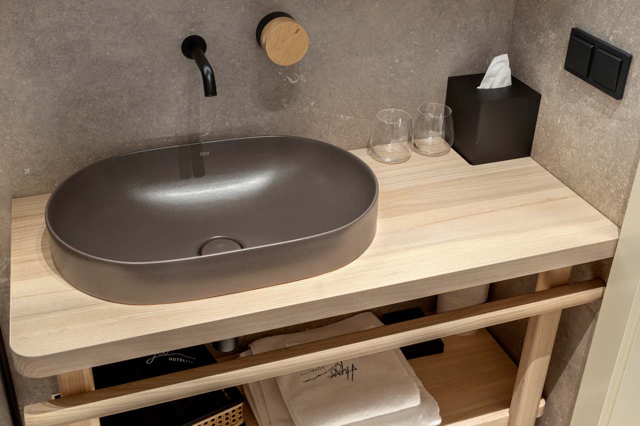 La prioridad en el diseño interior del hotel es garantizar que los huéspedes se vayan con una sonrisa, sintiéndose relajados y completamente satisfechos. Adoptando el enfoque minimalista del hygge, el diseño transmite una agradable sensación de confort a través de una cuidada selección de colores y mobiliario en materiales naturales con suaves curvas y formas orgánicas. En perfecta sintonía con la filosofía hygge, las líneas suaves y las formas redondeadas del lavabo Beyond de color café y del inodoro y bidé Inspira irradian relajación, calidez y armonía. El diseño de la colección Ona, inspirado en la naturaleza, se suma a la estética relajante. Los bidés y lavabos suspendidos contribuyen a crear una sensación de amplitud y equilibrio que evoca la serenidad de los paisajes tranquilos. De esta forma, el confort y el hygge se transmiten a todos los huéspedes del hotel. Los aseos públicos para hombres cuentan con los minimalistas urinarios Proton y los aseos accesibles están equipados con inodoros Access y asas de baño, garantizando un entorno acogedor e inclusivo para todos.23