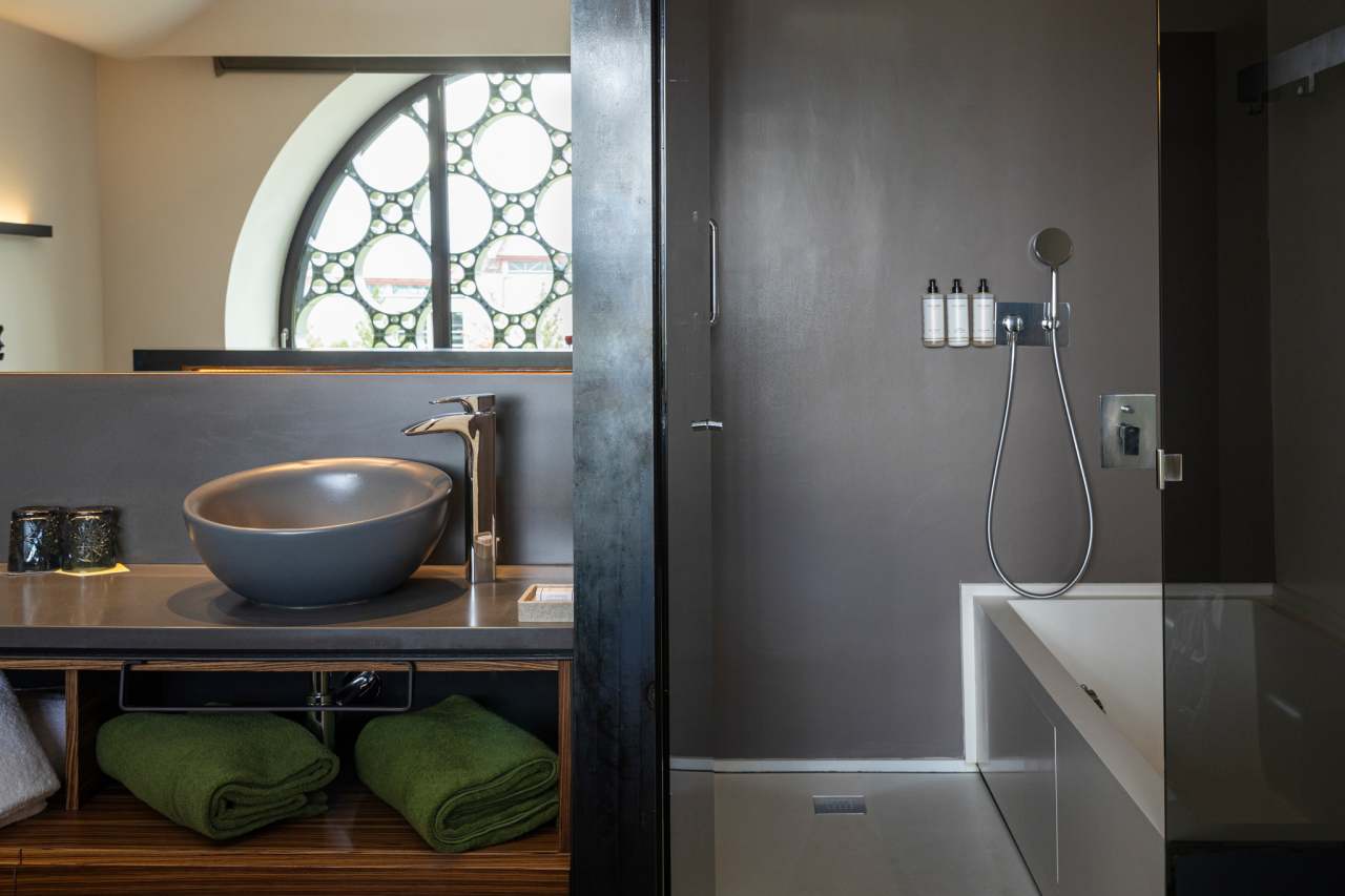 El diseño de este hotel boutique de 13 habitaciones se inspira en el apilado horizontal de las botellas de cava y en la técnica del trencadís de Antoni Gaudí. Las líneas sinuosas, los grandes ventanales circulares y los motivos geométricos, junto con el uso de materiales naturales, crean un conjunto equilibrado en perfecta armonía con el entorno. Los modernos baños de planta abierta cuentan con lavabos Bol en acabado grafito, la elegante grifería de lavabo Thesis y los originales inodoros Happening. La decidida apuesta por la sostenibilidad, patente en el cuidado diseño del edificio y las buenas prácticas sostenibles, también se refleja en los productos Roca, que contribuyen a la eficiencia energética y la durabilidad.4