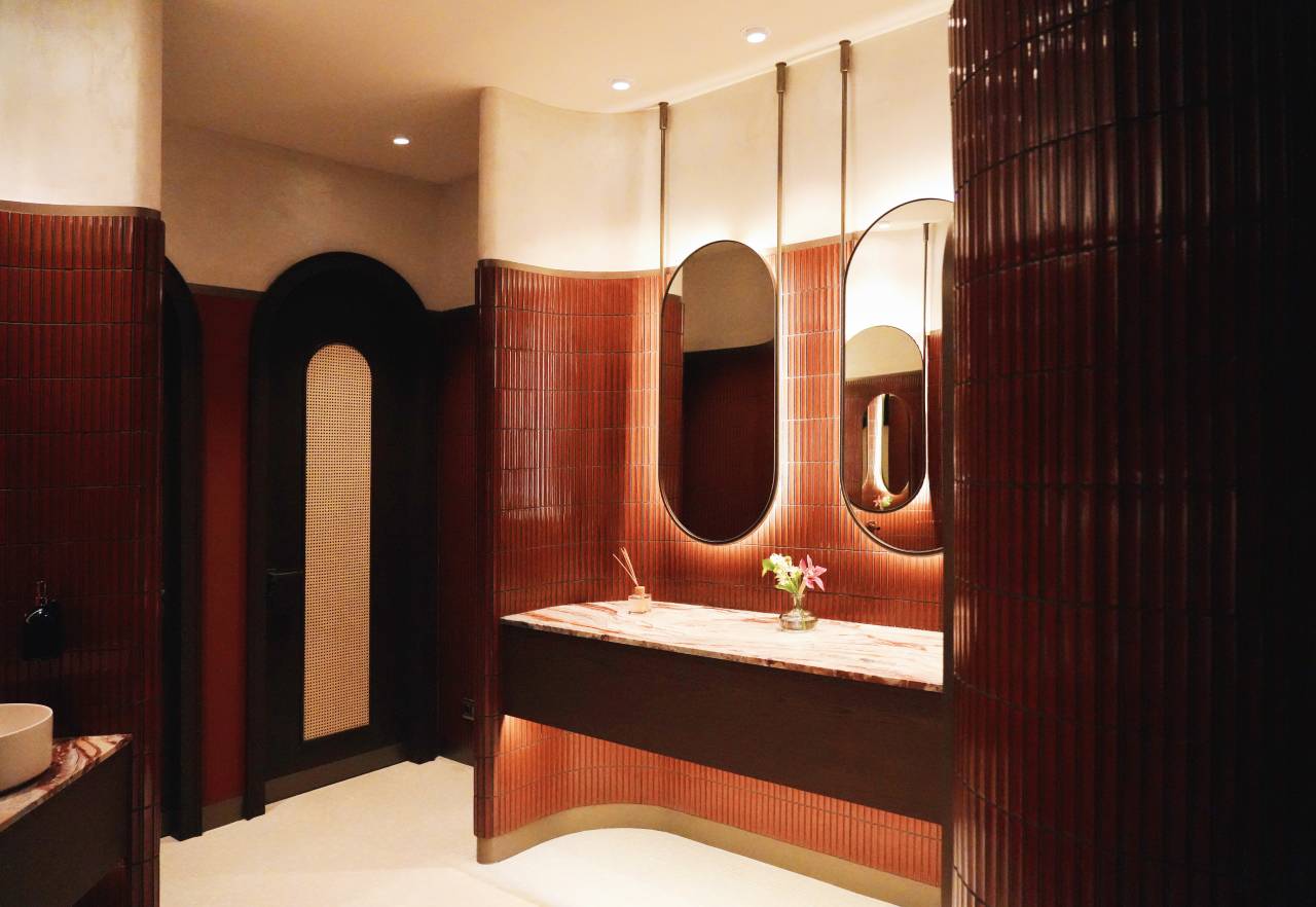 Los espacios de baño son las zonas más íntimas del restaurante y en ellos se ha optado por un diseño de líneas curvas que invita al confort. El lavabo sobre encimera de Fineceramic® Inspira Round ofrece un contrapunto orgánico a las singulares paredes curvas de los baños. La grifería electrónica de lavabo L30-E añade un plus de diseño al espacio y garantiza la eficiencia hídrica, en línea con el concepto del «Árbol de la vida». Entre los accesorios se encuentran la percha Cubica y el escobillero de pared mural Victoria, modelos minimalistas y discretos que ofrecen la máxima funcionalidad. Por otro lado, el inodoro suspendido Rimless Dama, con asiento con caída amortiguada y placa de accionamiento dual In-Wall PL10 (One), aporta un toque de modernidad y complementa el estilo acogedor y natural del espacio de baño.7