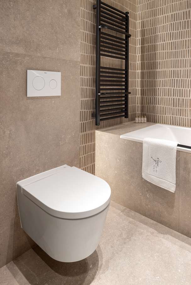 La prioridad en el diseño interior del hotel es garantizar que los huéspedes se vayan con una sonrisa, sintiéndose relajados y completamente satisfechos. Adoptando el enfoque minimalista del hygge, el diseño transmite una agradable sensación de confort a través de una cuidada selección de colores y mobiliario en materiales naturales con suaves curvas y formas orgánicas. En perfecta sintonía con la filosofía hygge, las líneas suaves y las formas redondeadas del lavabo Beyond de color café y del inodoro y bidé Inspira irradian relajación, calidez y armonía. El diseño de la colección Ona, inspirado en la naturaleza, se suma a la estética relajante. Los bidés y lavabos suspendidos contribuyen a crear una sensación de amplitud y equilibrio que evoca la serenidad de los paisajes tranquilos. De esta forma, el confort y el hygge se transmiten a todos los huéspedes del hotel. Los aseos públicos para hombres cuentan con los minimalistas urinarios Proton y los aseos accesibles están equipados con inodoros Access y asas de baño, garantizando un entorno acogedor e inclusivo para todos.27