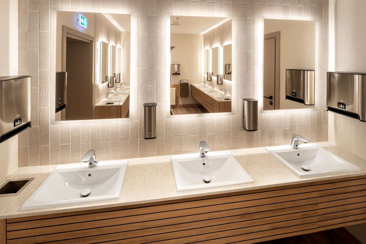 El interiorismo, obra de Tremend Studio, presenta un diseño armonioso caracterizado por el uso de tonos cálidos y naturales con detalles en madera que crean un ambiente agradable y relajado. Los baños de las habitaciones cuentan con confortables bañeras encastradas o duchas walk-in y mamparas de cristal, que generan una sensación de amplitud y espaciosidad. La atmósfera exclusiva y acogedora de estos baños se logra gracias a los muebles con acabados en madera, los lavabos Diverta sobre encimera y los inodoros The Gap Rimless. Por otro lado, los baños públicos también destacan por su minimalismo, con una planta diáfana en la que cobran protagonismo los lavabos Diverta y los urinarios Hall. Los espejos con iluminación LED integrada realzan el espacio con un suave resplandor y añaden al mismo tiempo un toque de sofisticación.10