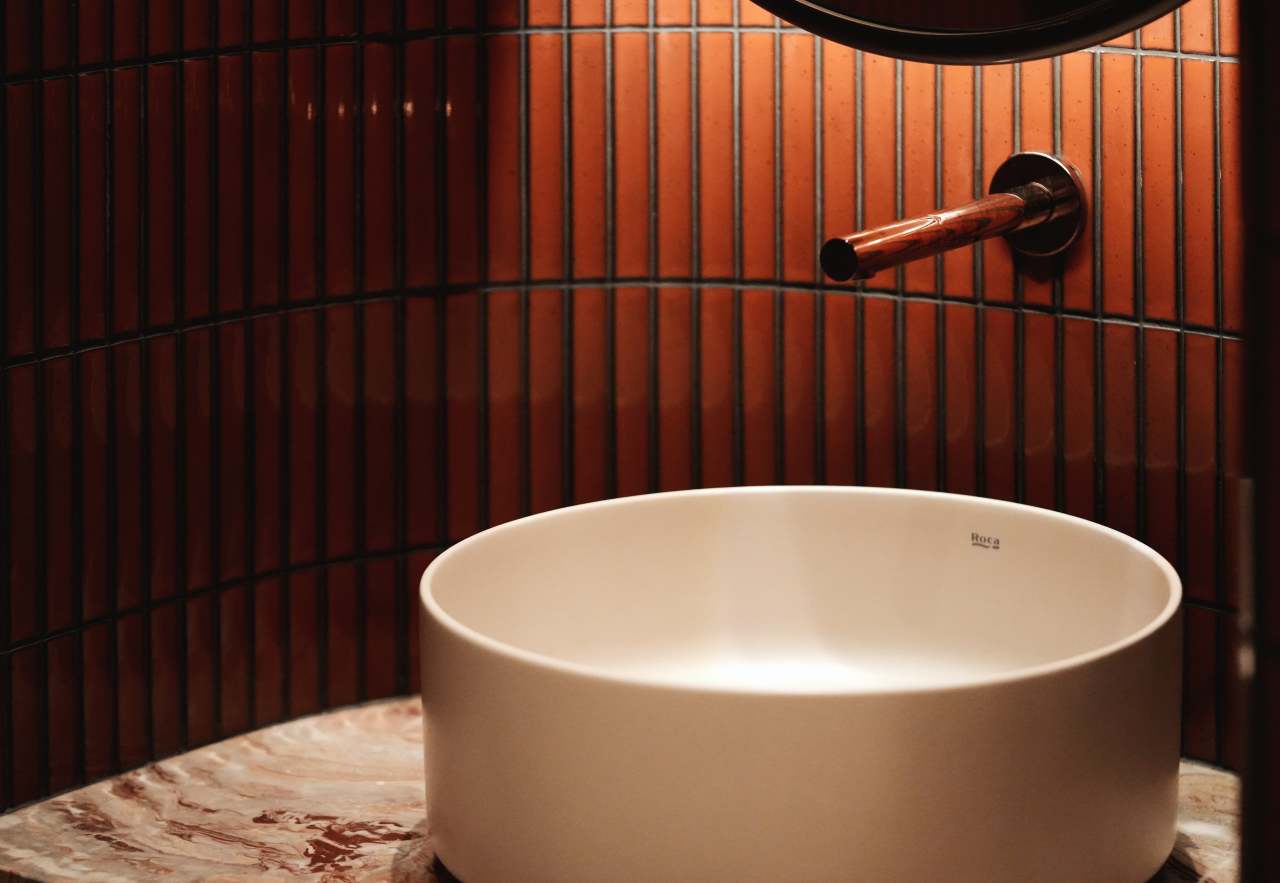 Los espacios de baño son las zonas más íntimas del restaurante y en ellos se ha optado por un diseño de líneas curvas que invita al confort. El lavabo sobre encimera de Fineceramic® Inspira Round ofrece un contrapunto orgánico a las singulares paredes curvas de los baños. La grifería electrónica de lavabo L30-E añade un plus de diseño al espacio y garantiza la eficiencia hídrica, en línea con el concepto del «Árbol de la vida». Entre los accesorios se encuentran la percha Cubica y el escobillero de pared mural Victoria, modelos minimalistas y discretos que ofrecen la máxima funcionalidad. Por otro lado, el inodoro suspendido Rimless Dama, con asiento con caída amortiguada y placa de accionamiento dual In-Wall PL10 (One), aporta un toque de modernidad y complementa el estilo acogedor y natural del espacio de baño.3