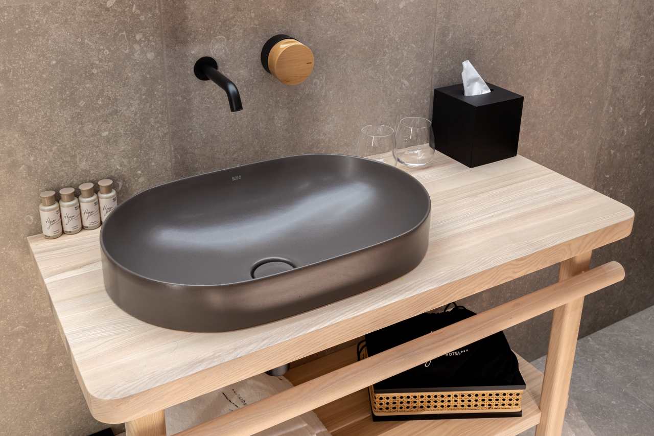 La prioridad en el diseño interior del hotel es garantizar que los huéspedes se vayan con una sonrisa, sintiéndose relajados y completamente satisfechos. Adoptando el enfoque minimalista del hygge, el diseño transmite una agradable sensación de confort a través de una cuidada selección de colores y mobiliario en materiales naturales con suaves curvas y formas orgánicas. En perfecta sintonía con la filosofía hygge, las líneas suaves y las formas redondeadas del lavabo Beyond de color café y del inodoro y bidé Inspira irradian relajación, calidez y armonía. El diseño de la colección Ona, inspirado en la naturaleza, se suma a la estética relajante. Los bidés y lavabos suspendidos contribuyen a crear una sensación de amplitud y equilibrio que evoca la serenidad de los paisajes tranquilos. De esta forma, el confort y el hygge se transmiten a todos los huéspedes del hotel. Los aseos públicos para hombres cuentan con los minimalistas urinarios Proton y los aseos accesibles están equipados con inodoros Access y asas de baño, garantizando un entorno acogedor e inclusivo para todos.12