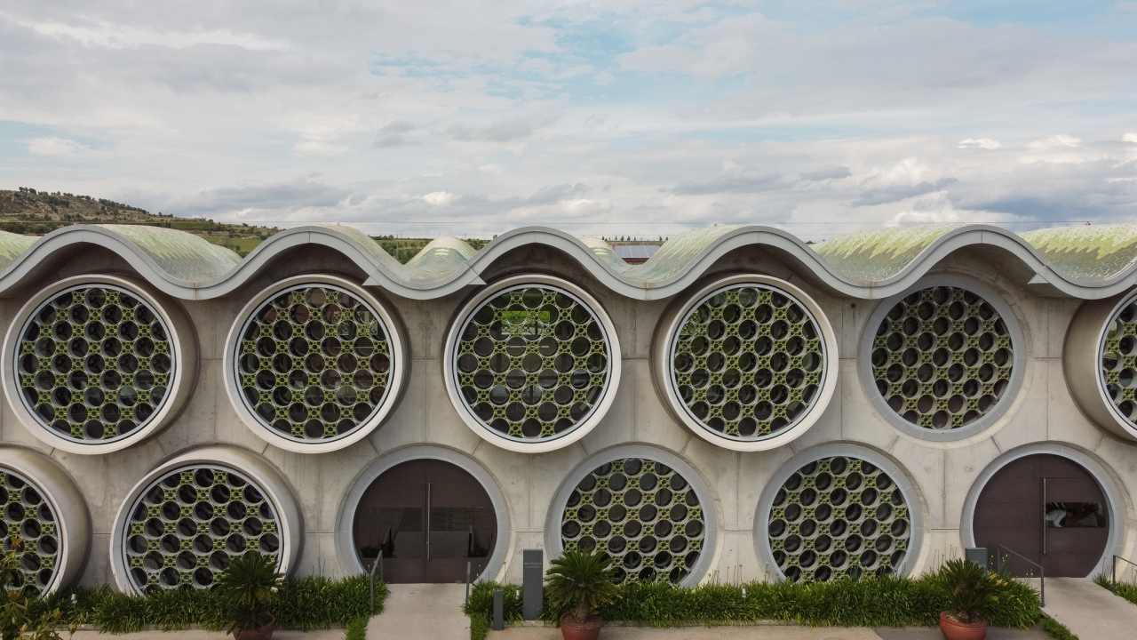 El diseño de este hotel boutique de 13 habitaciones se inspira en el apilado horizontal de las botellas de cava y en la técnica del trencadís de Antoni Gaudí. Las líneas sinuosas, los grandes ventanales circulares y los motivos geométricos, junto con el uso de materiales naturales, crean un conjunto equilibrado en perfecta armonía con el entorno. Los modernos baños de planta abierta cuentan con lavabos Bol en acabado grafito, la elegante grifería de lavabo Thesis y los originales inodoros Happening. La decidida apuesta por la sostenibilidad, patente en el cuidado diseño del edificio y las buenas prácticas sostenibles, también se refleja en los productos Roca, que contribuyen a la eficiencia energética y la durabilidad.10